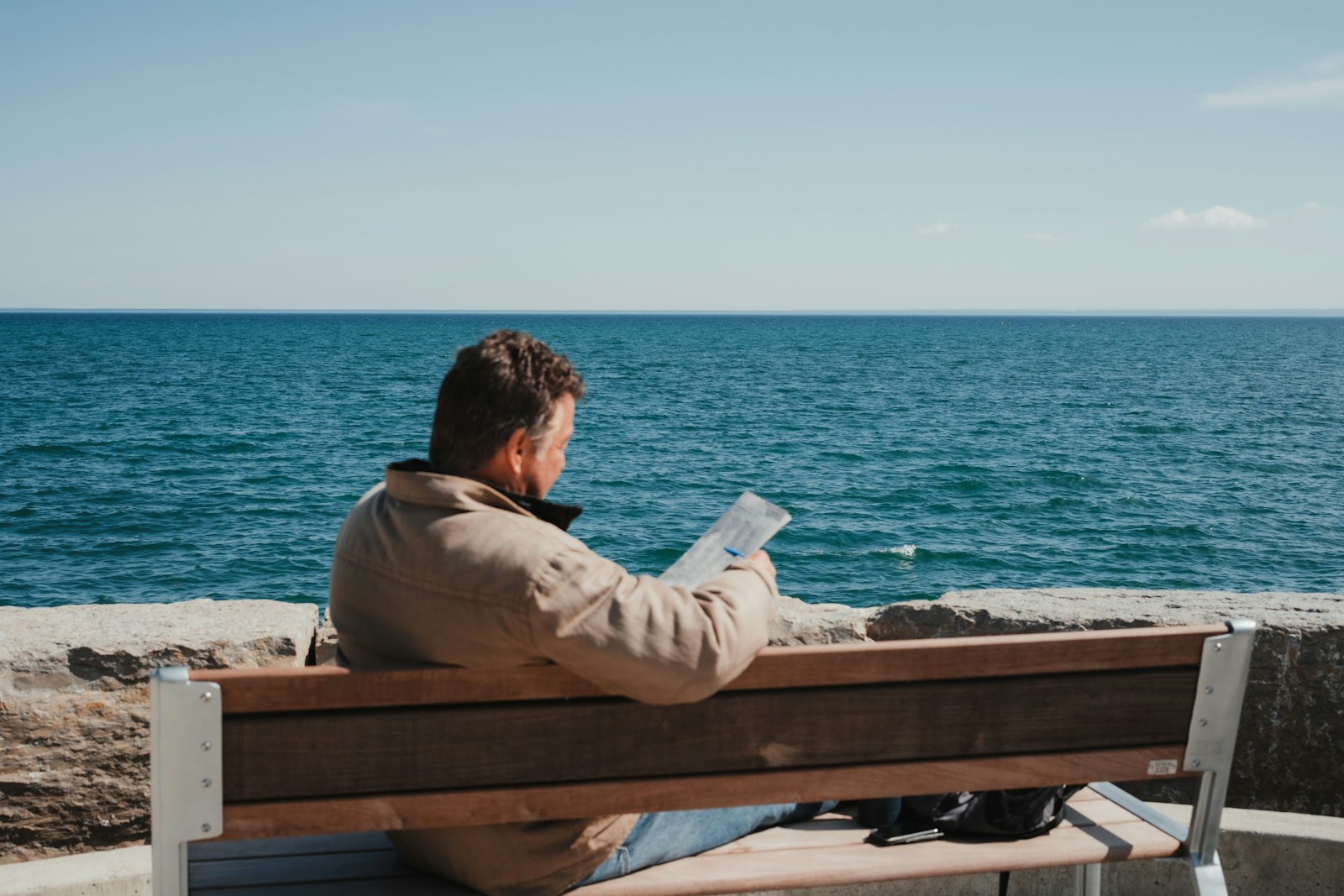 A man reads while gazing at the ocean.